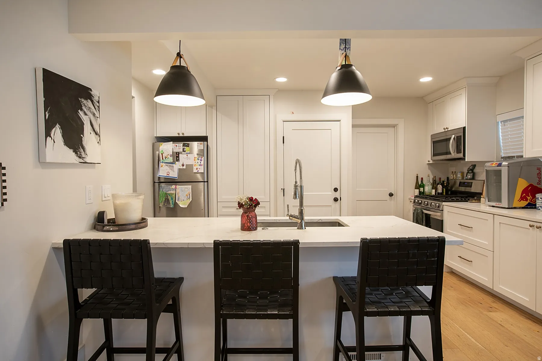 Kitchen featuring a kitchen bar, stainless steel appliances, a peninsula, and white cabinetry