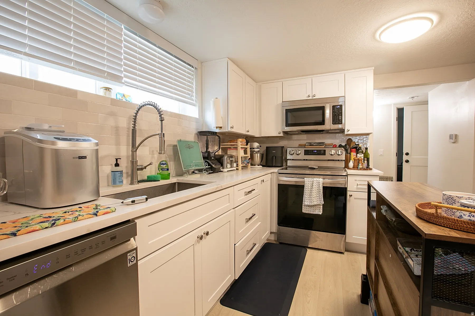 Kitchen featuring stainless steel appliances, white cabinetry, light wood-style flooring, and wooden counters