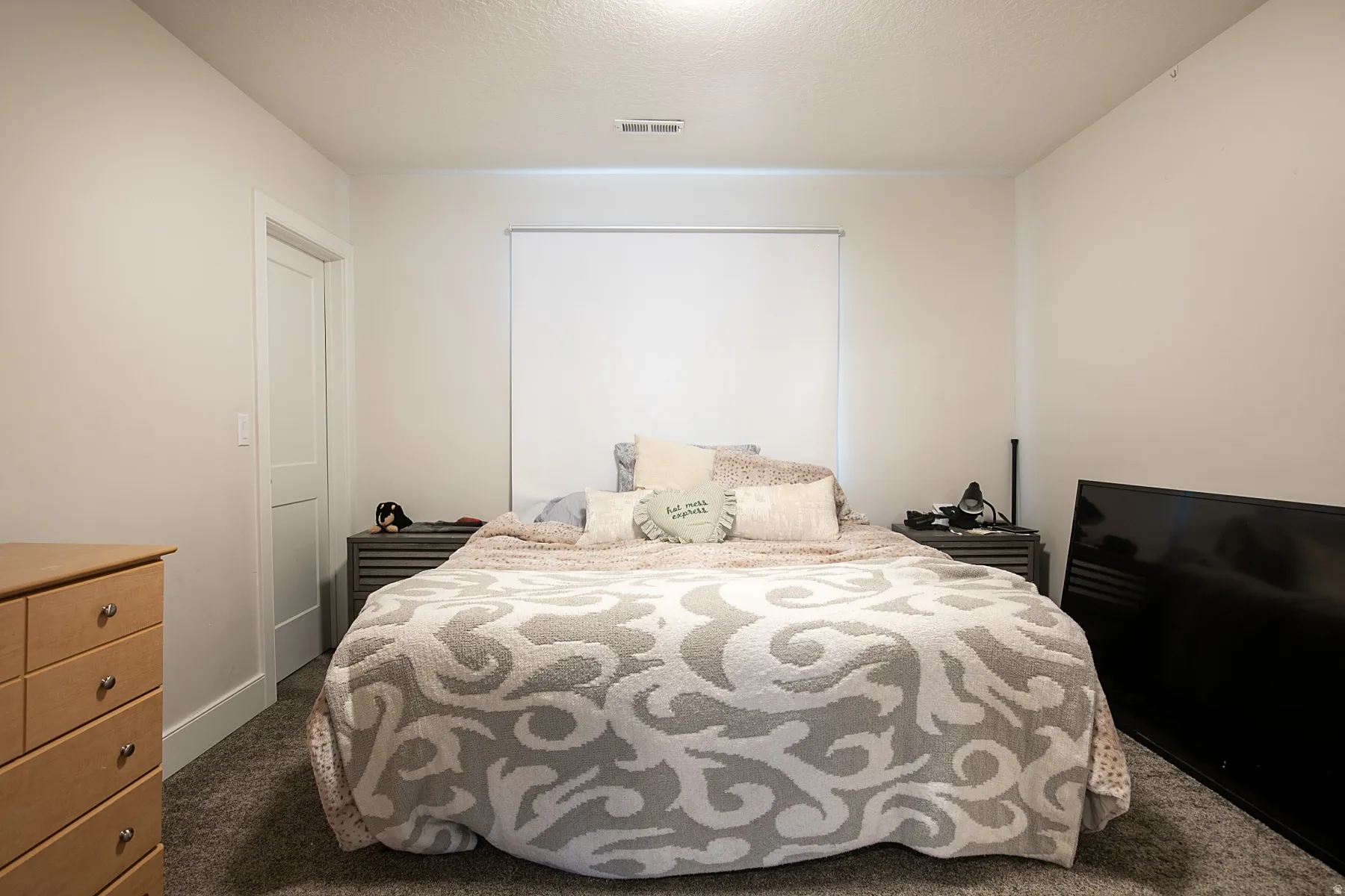 Bedroom with dark carpet and a textured ceiling