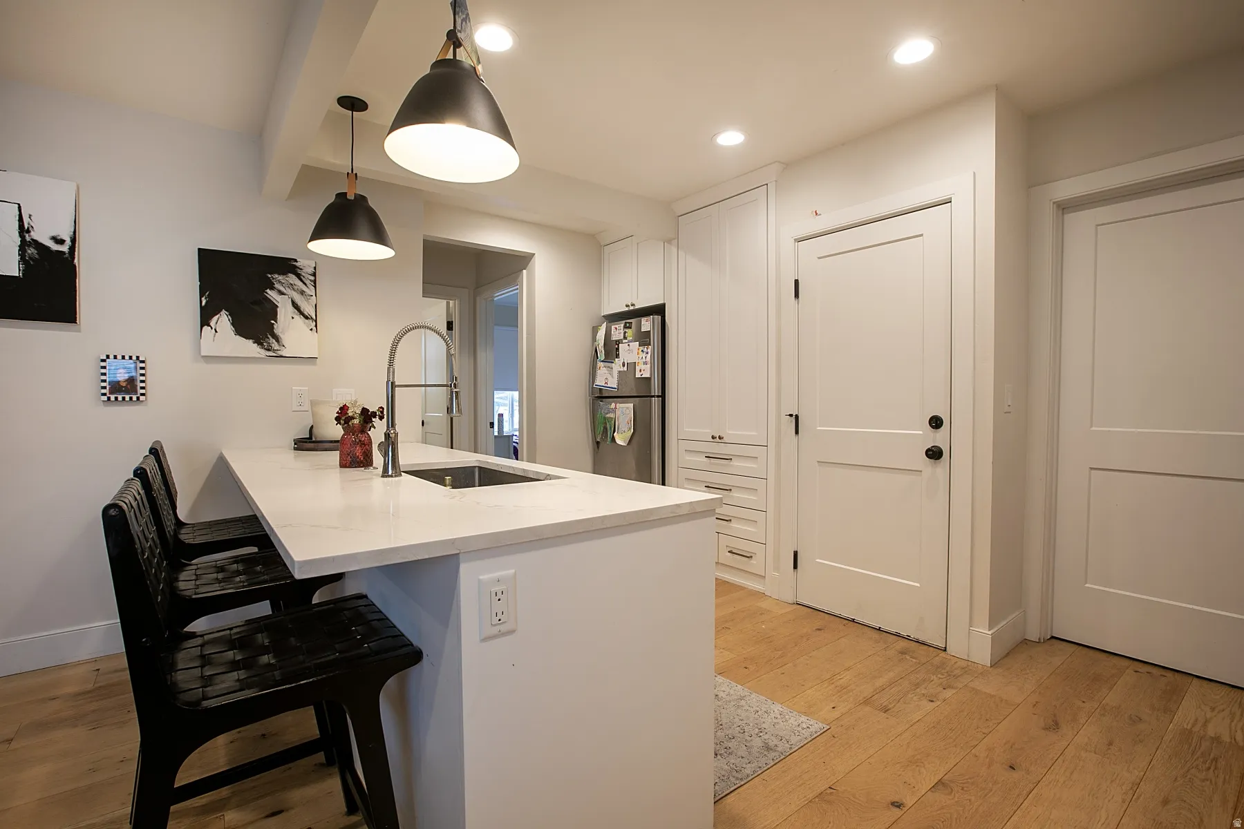 Kitchen with a peninsula, white cabinets, a kitchen bar, and light wood-style flooring