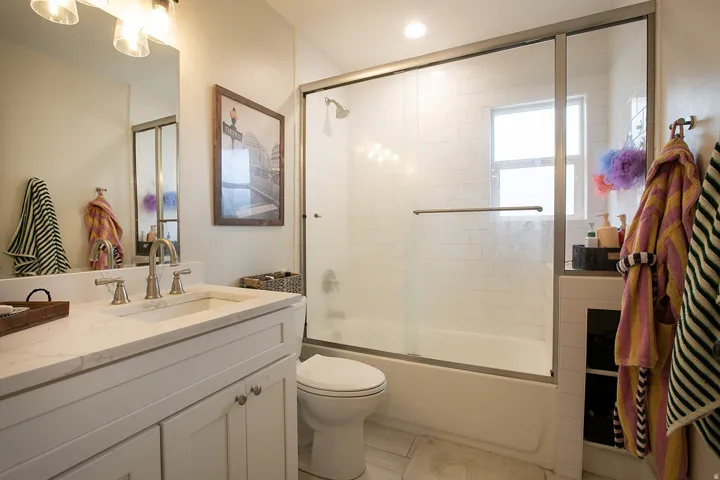 Bathroom featuring vanity, enclosed tub / shower combo, light tile patterned flooring, and recessed lighting