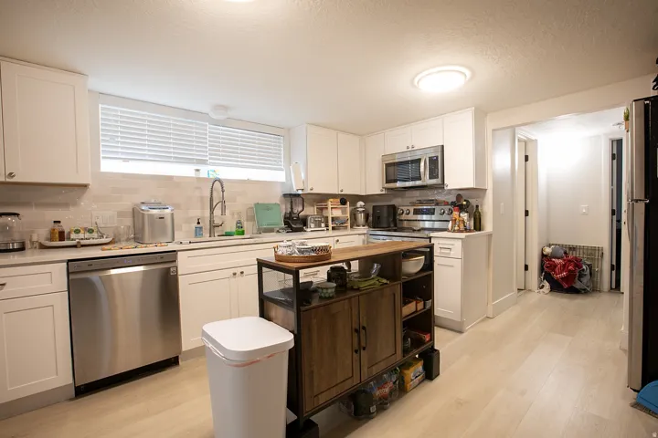 Kitchen with white cabinetry, light wood-type flooring, stainless steel appliances, tasteful backsplash, and a textured ceiling