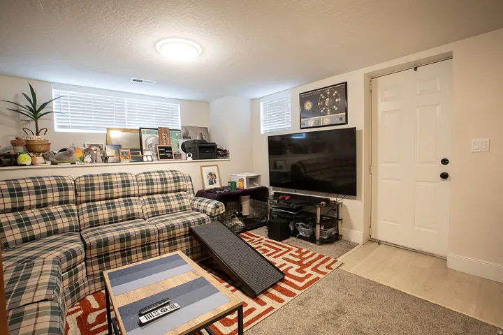 Living room with a textured ceiling, light colored carpet, and light wood-type flooring