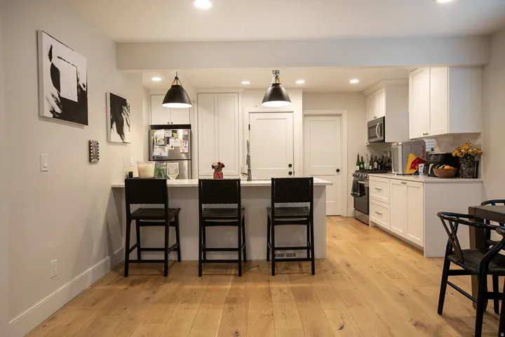 Kitchen featuring a peninsula, light countertops, white cabinetry, stainless steel appliances, and light wood-style floors