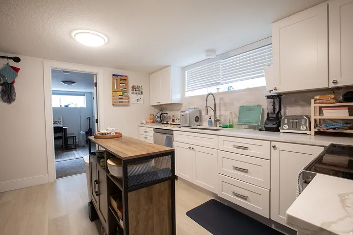 Kitchen with white cabinets, tasteful backsplash, electric range, light wood finished floors, and a textured ceiling
