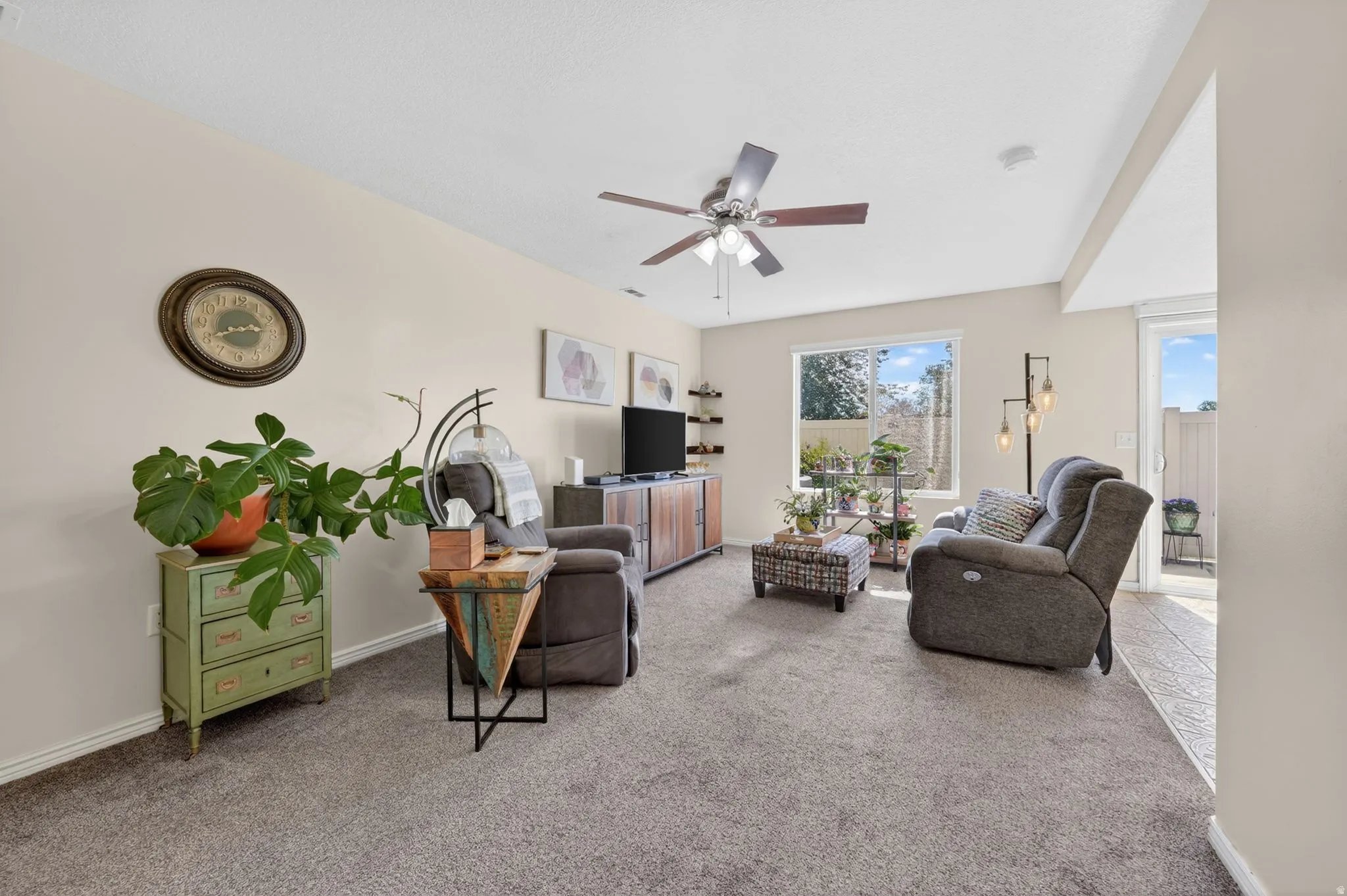 Carpeted living room with a ceiling fan and baseboards