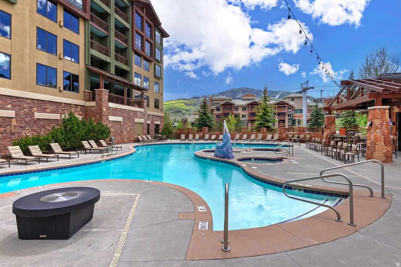Resort-style pool area featuring a freeform swimming pool, integrated spas, and a concrete deck