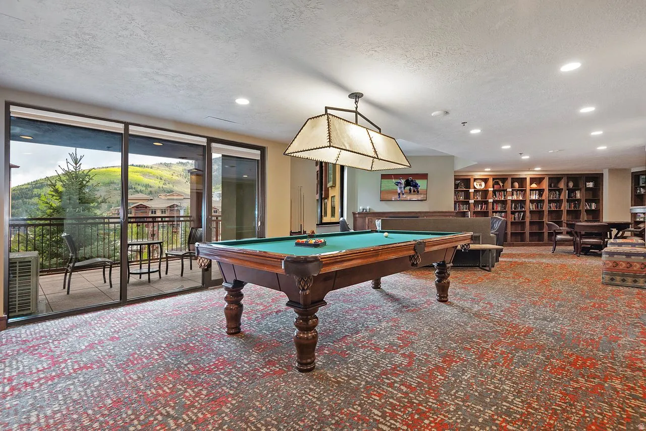 Spacious recreation room featuring a billiard table, recessed lighting, and a full-wall built-in bookcase
