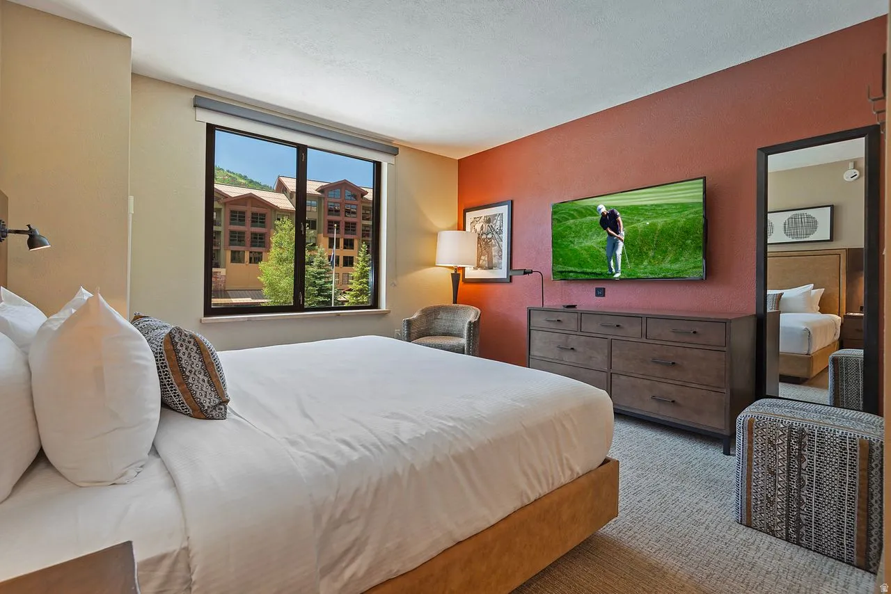Spacious bedroom featuring neutral wall tones, a large window, and light-colored carpeting