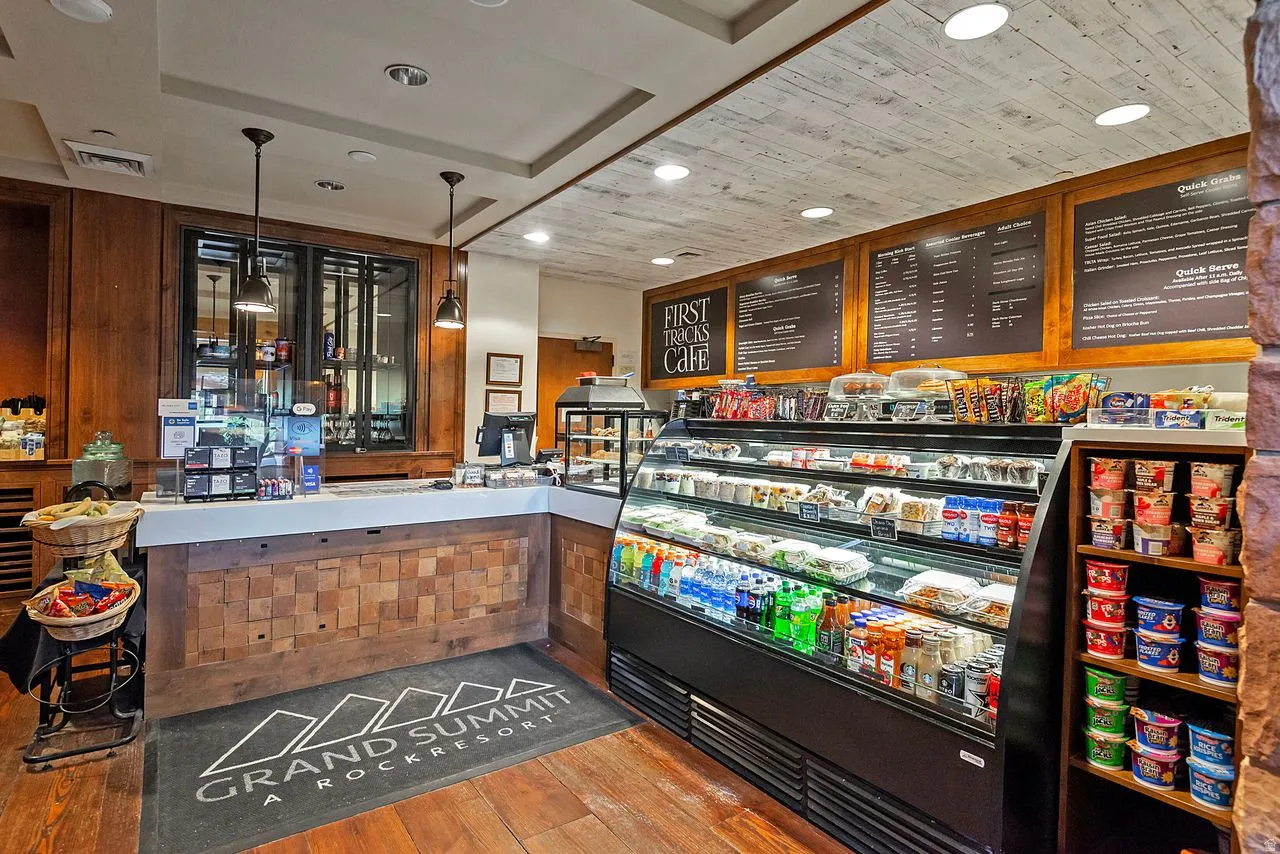 Retail counter area featuring a white countertop, wood-finish flooring, and a patterned wood-finish counter facade
