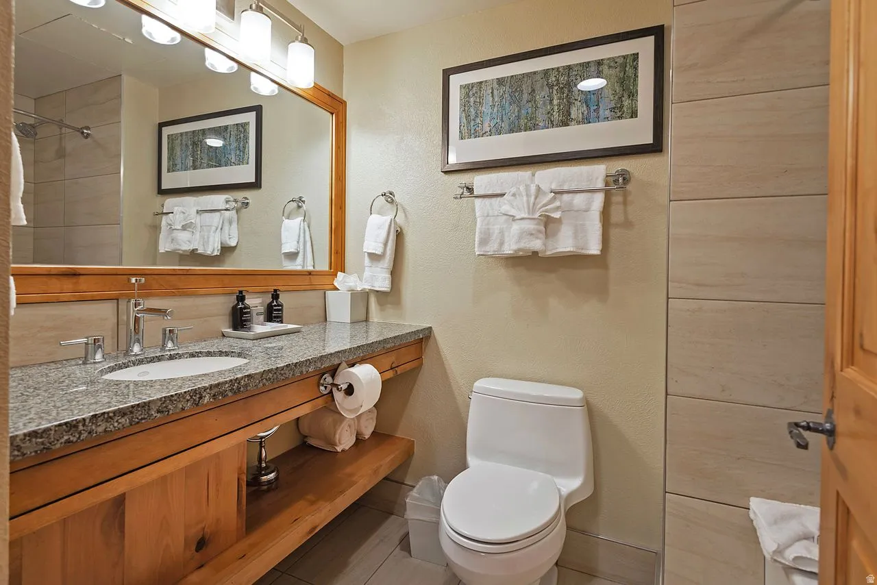 Bathroom vanity featuring a granite countertop, undermount sink, and wood-finish cabinetry