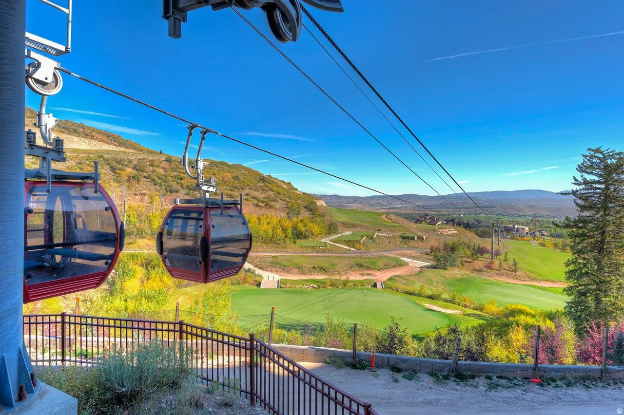 Gondola access with panoramic mountain and valley scenery, featuring rolling green fairways and distant structures