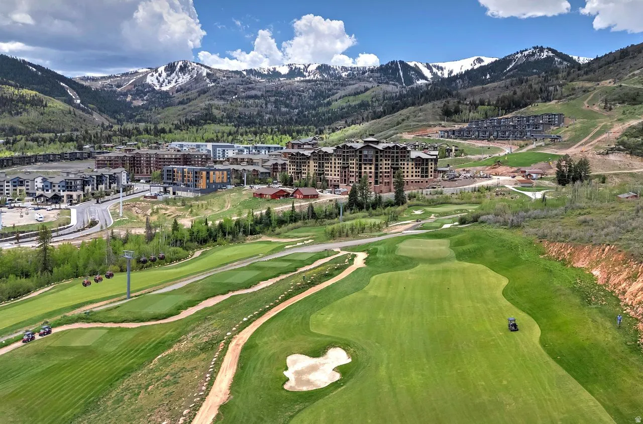 Expansive golf course terrain featuring manicured greens and sand traps, with a mountain backdrop