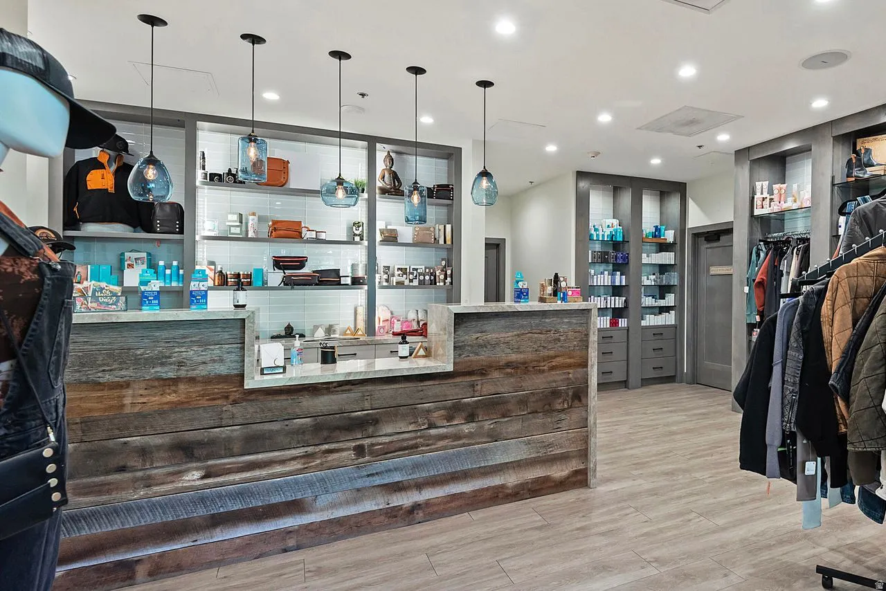 Commercial interior featuring a reclaimed wood-finish reception counter with a light-toned countertop, multiple pendant lights, recessed ceiling lighting, and wood-finish flooring