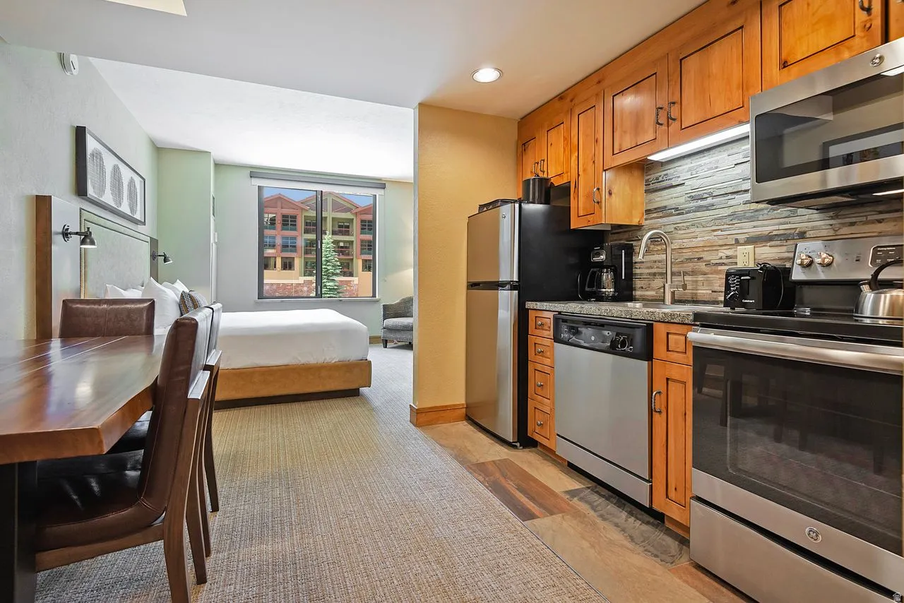 Compact kitchen featuring stainless steel appliances, wood cabinetry, and a textured backsplash
