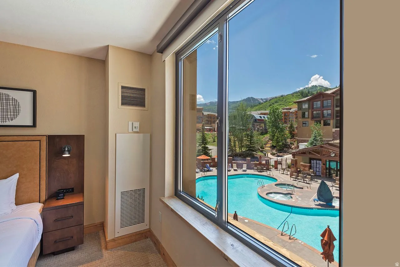Expansive window framing a mountain and pool area