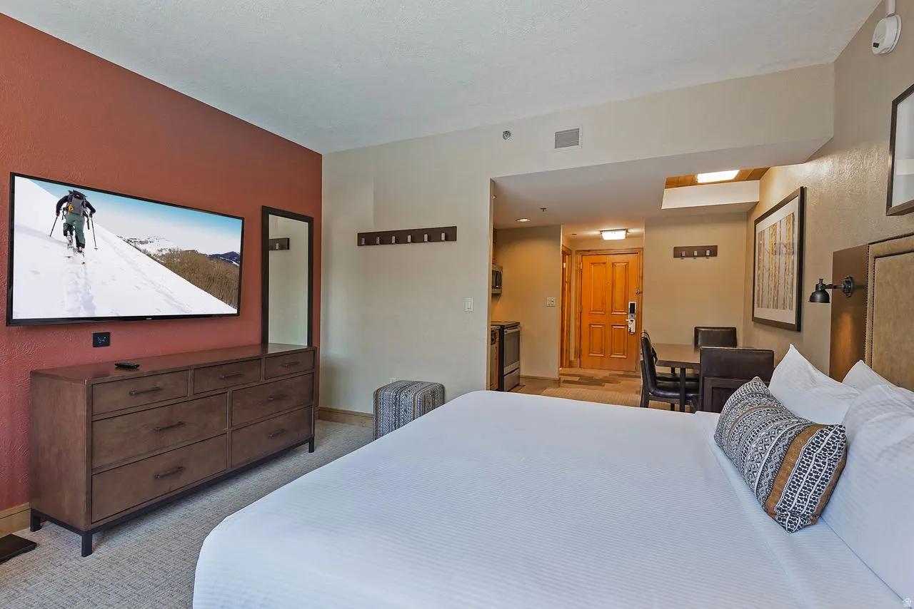 Open-concept living space with a distinct sleeping area featuring a large bed, and a dining area with a table and chairs