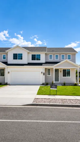 Contemporary townhome featuring a two-car garage, concrete driveway, and front lawn