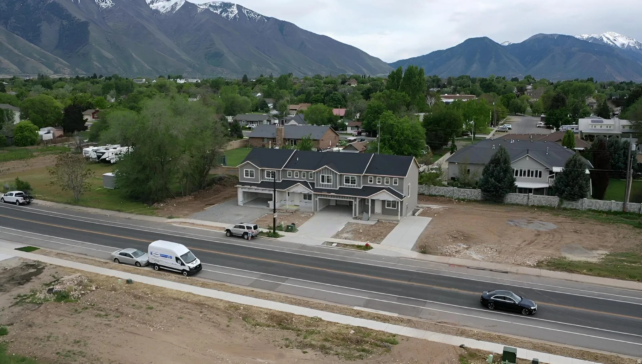 Modern gray siding townhome with white trim and black shingle roof