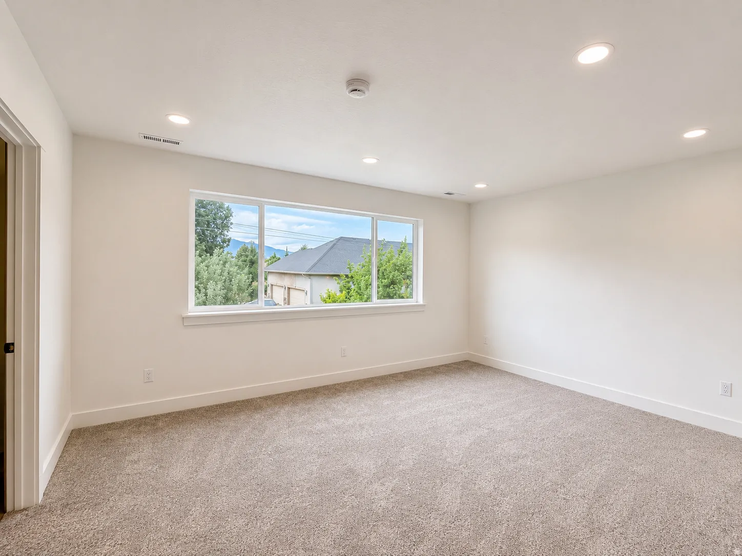 Spacious room featuring neutral carpet flooring, recessed lighting, and a large picture window
