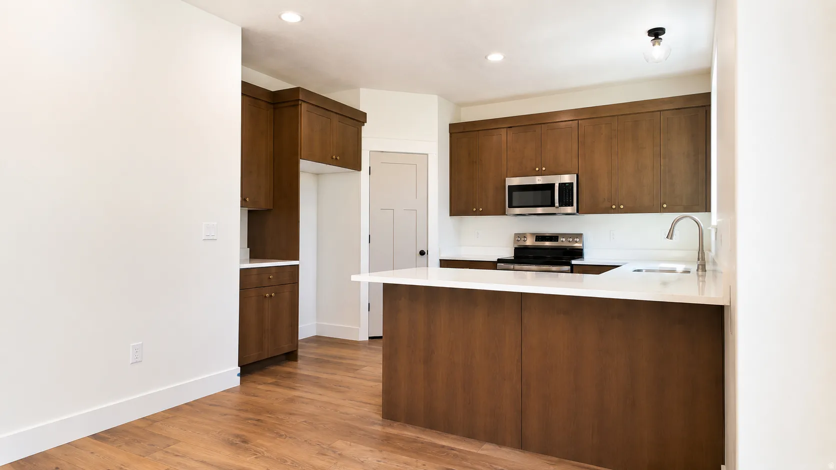 Kitchen featuring wood-finish flooring, recessed lighting, and a kitchen island with a white countertop