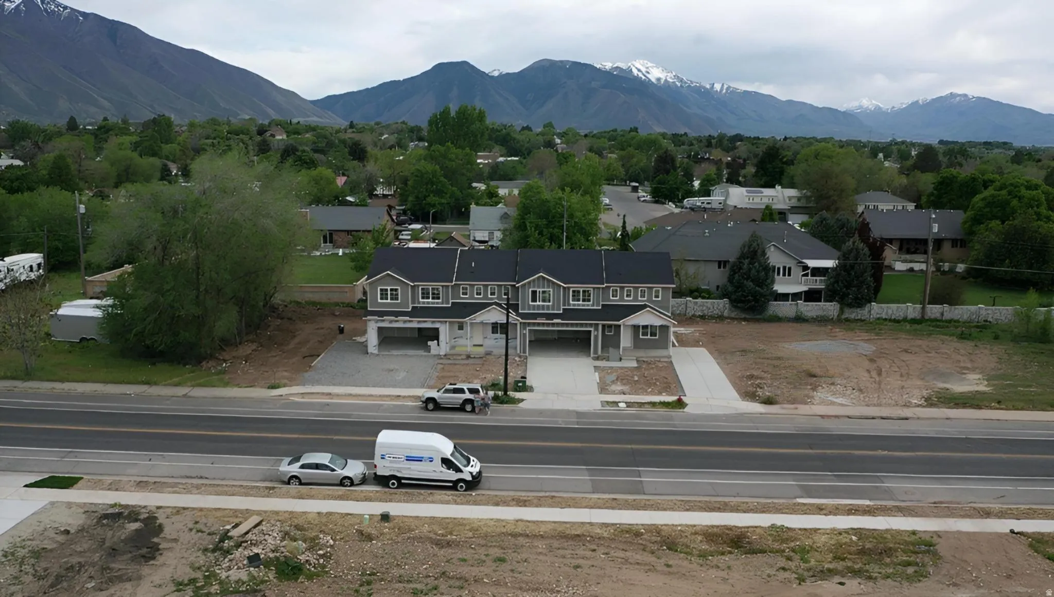 New construction townhome development featuring a gray facade, white trim, and dark roofing