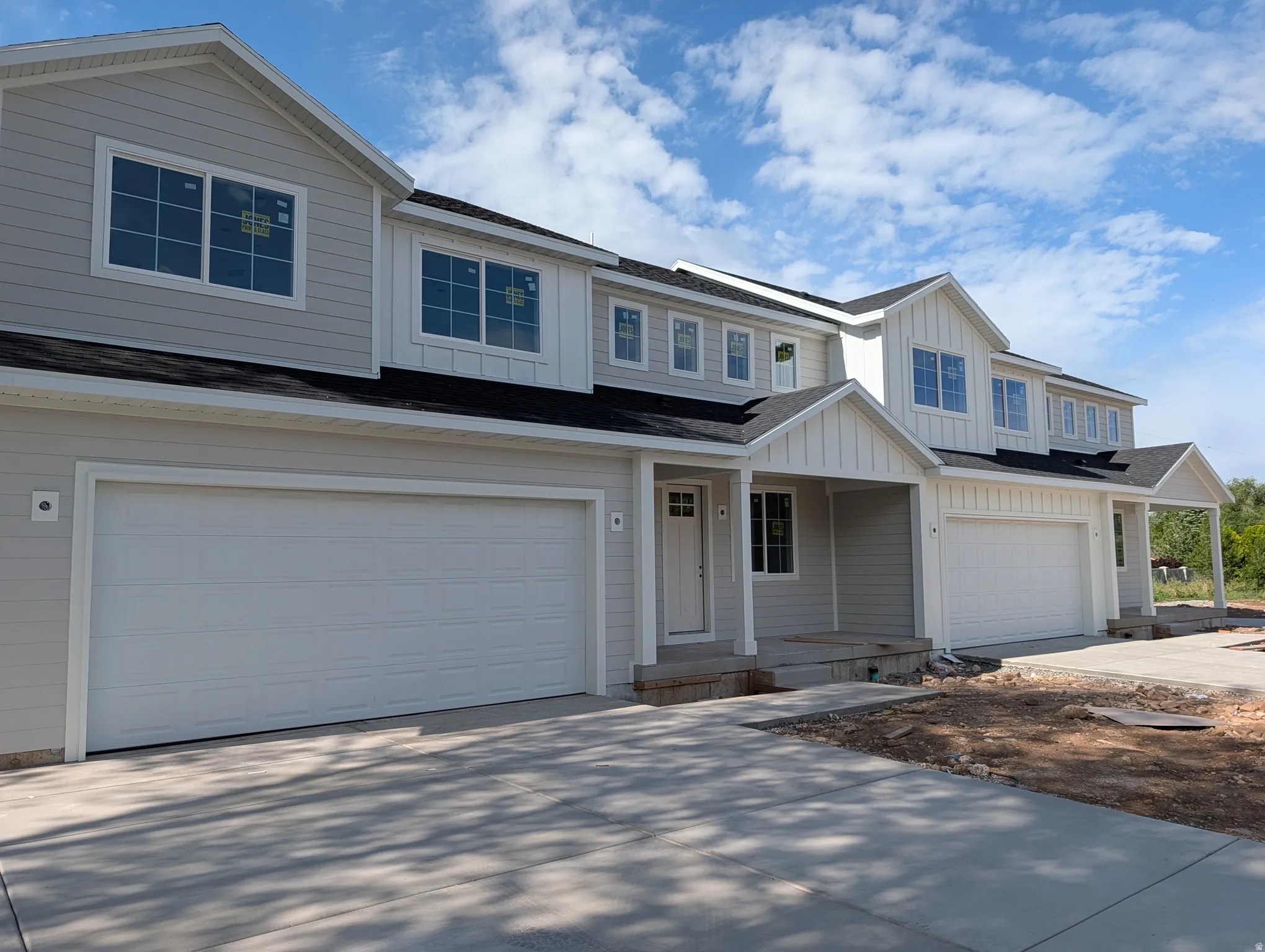 Contemporary multi-unit residence featuring light gray horizontal siding and contrasting white vertical board and batten accents