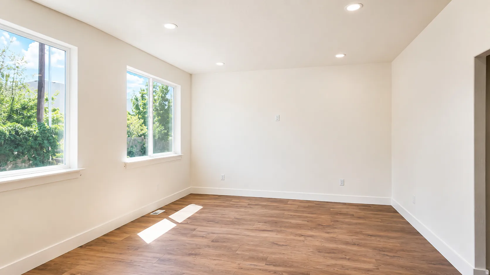 Bright room with wood-finish flooring, recessed lighting, and two large windows