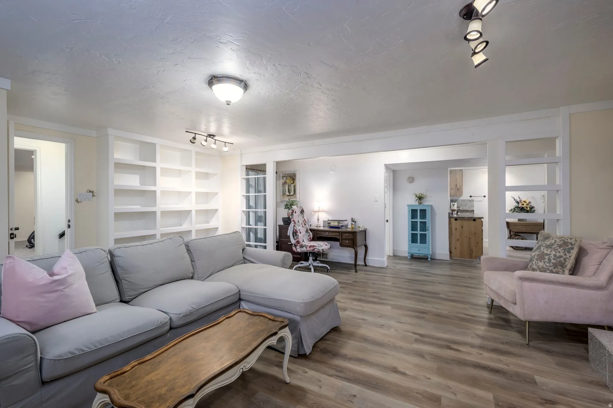 Spacious living area featuring extensive built-in shelving, wood-finish flooring, and recessed lighting