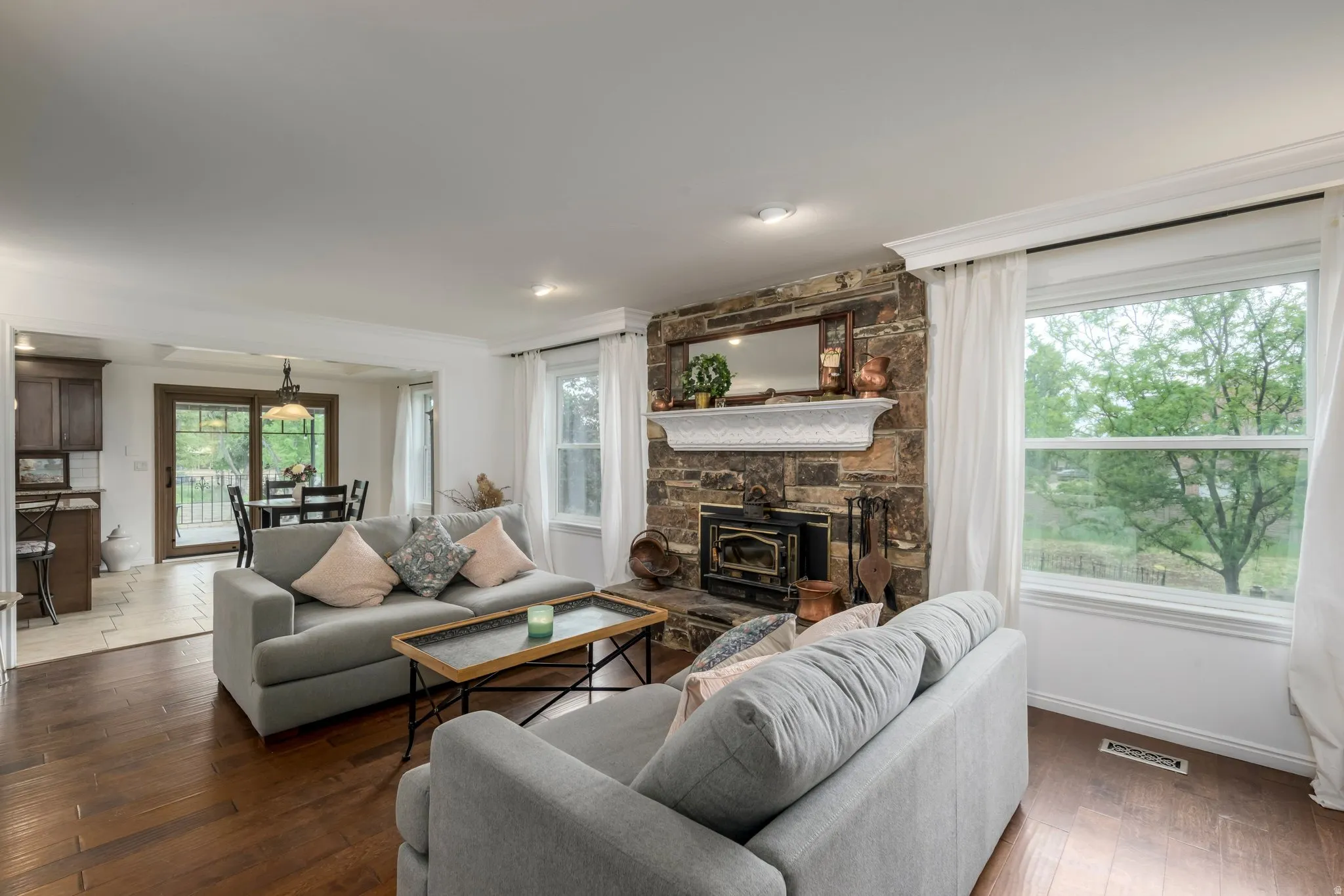 Family Room featuring hardwood flooring, a stone-faced fireplace with a white mantel, and two large windows
