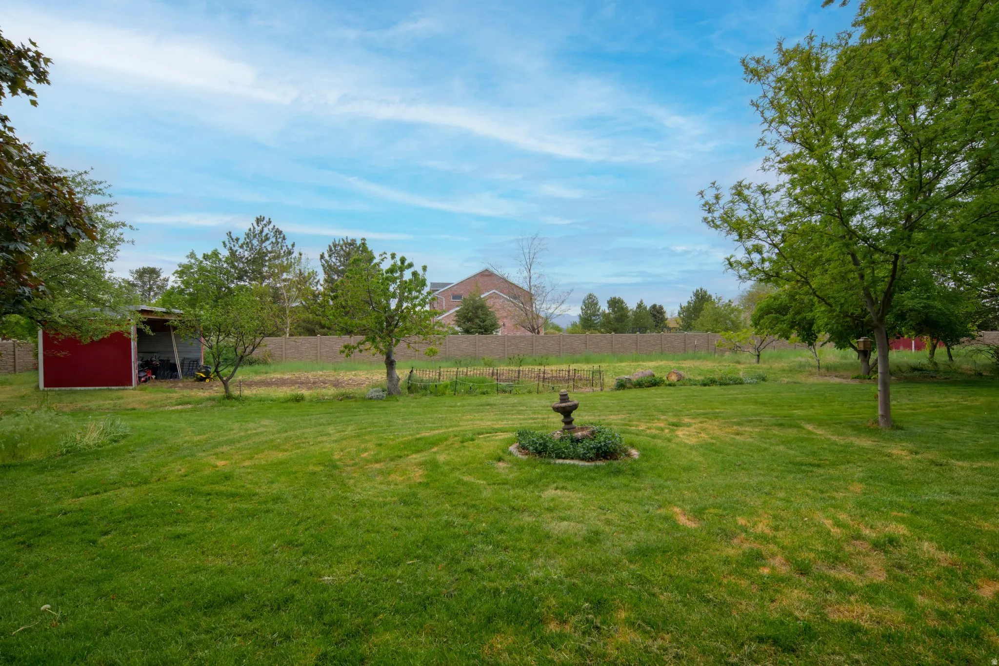 Expansive green lawn featuring mature trees and a decorative garden fountain