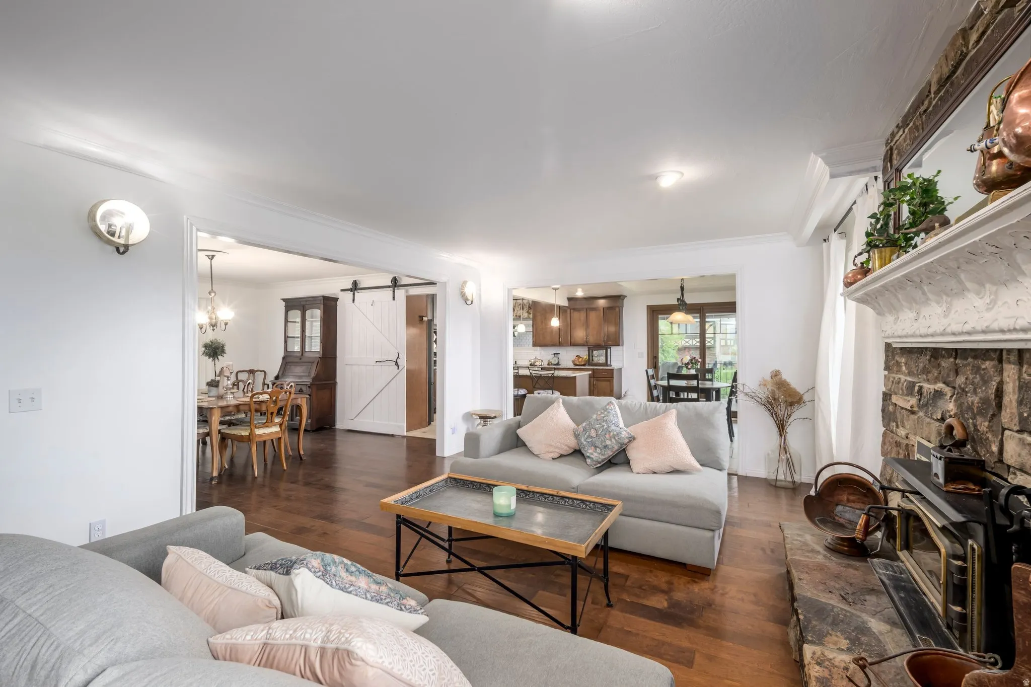 Family Room featuring wood-finish flooring, a stone-faced fireplace with a mantel, and crown molding