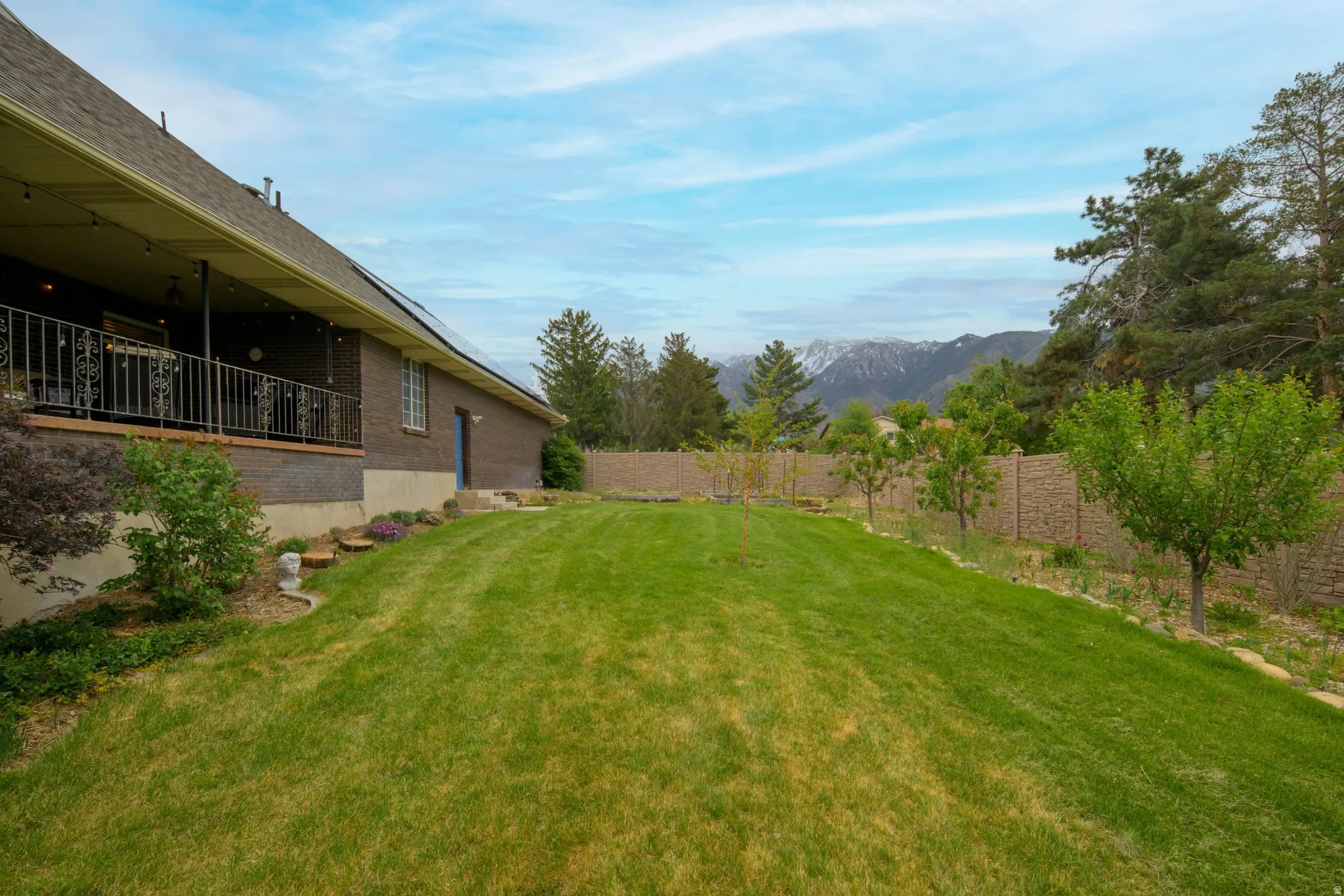 Expansive backyard featuring a lush lawn, mature trees, and a privacy fence