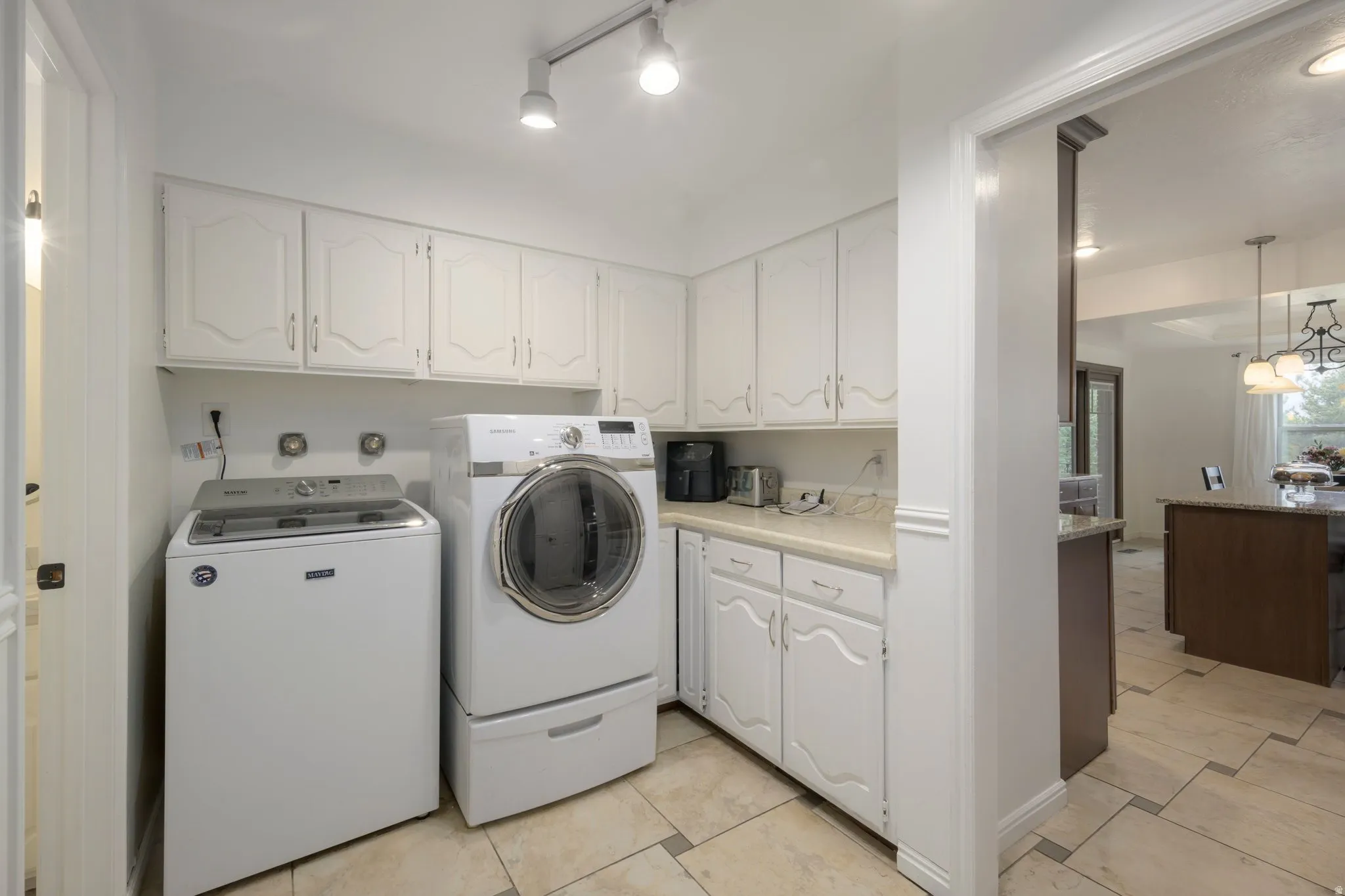 Laundry area featuring white cabinetry, a light-toned countertop, and tile flooring