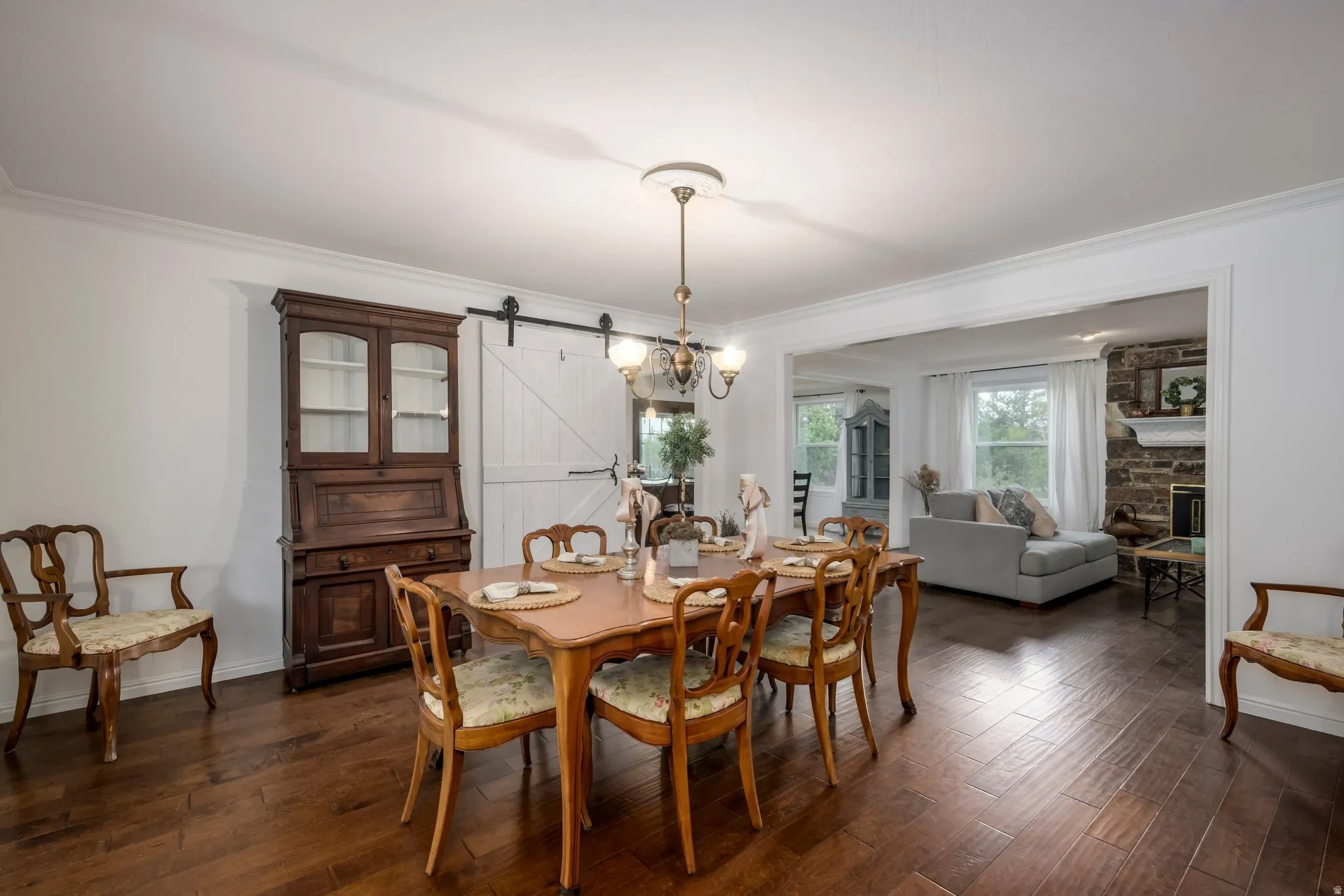 Dining area featuring wood-finish flooring, crown molding, a decorative chandelier, and a barn door