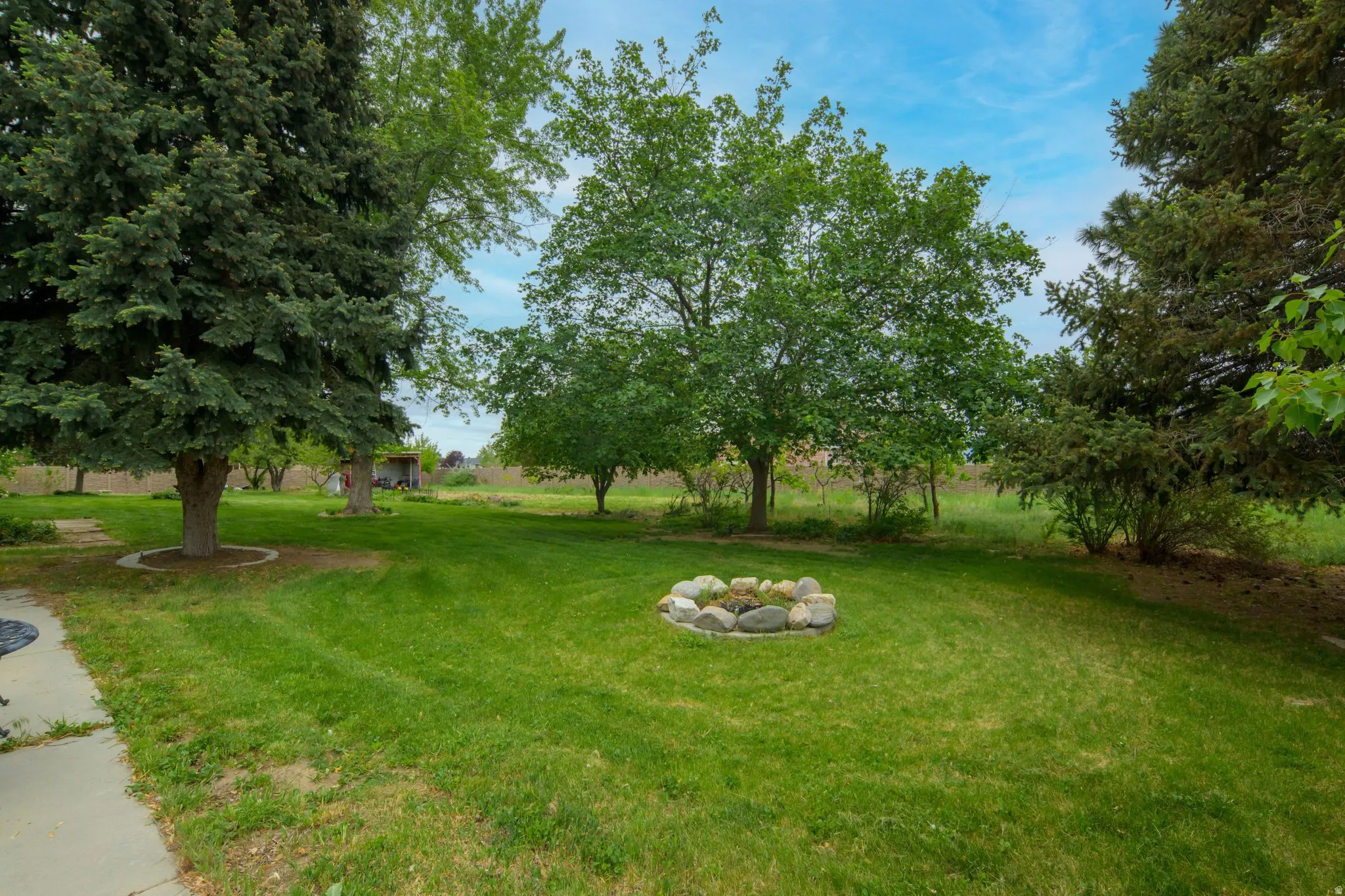 Expansive green lawn featuring a stone-lined fire pit