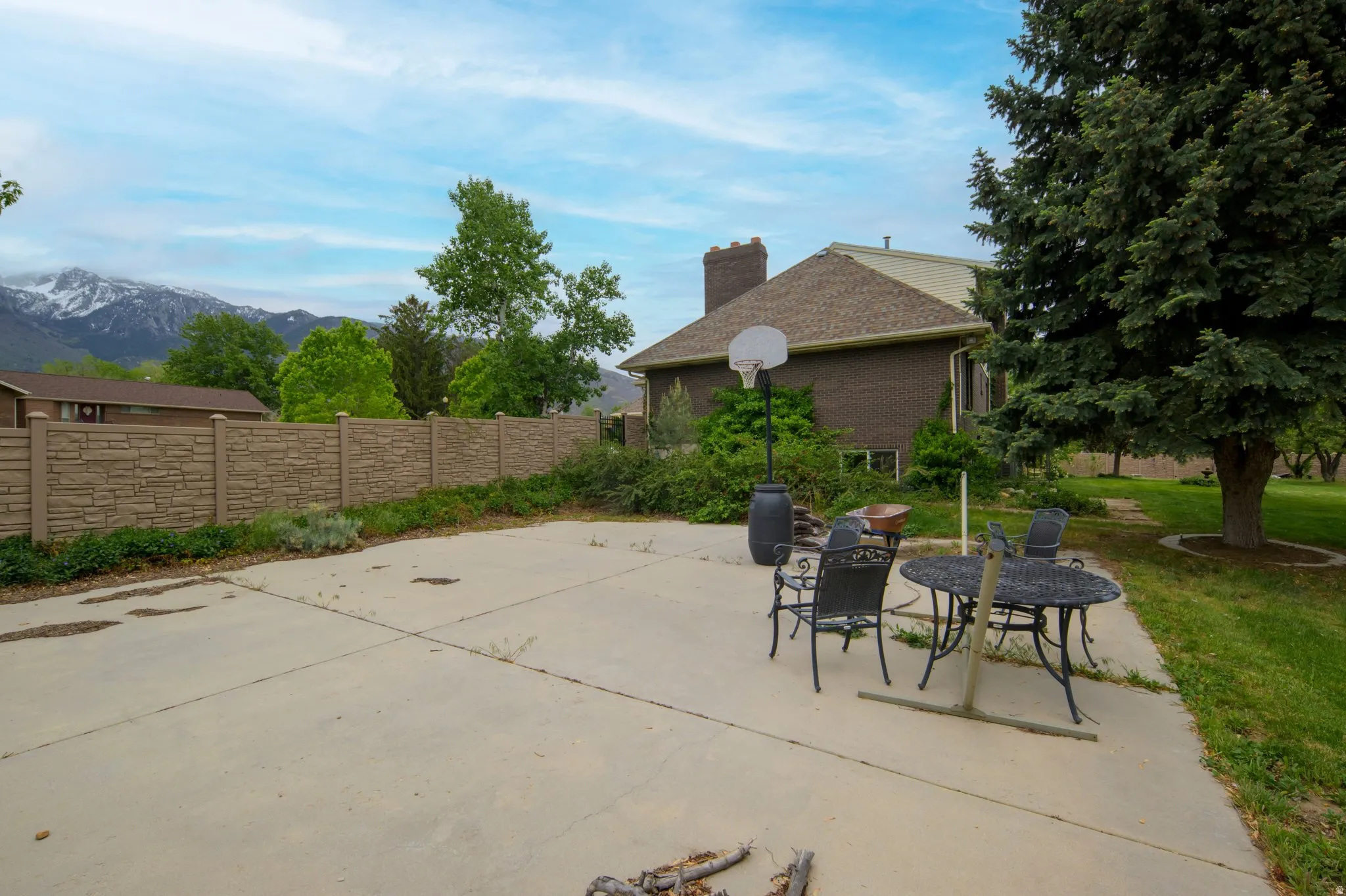 Expansive concrete patio with a structured stone-look privacy fence and a backdrop of distant mountains