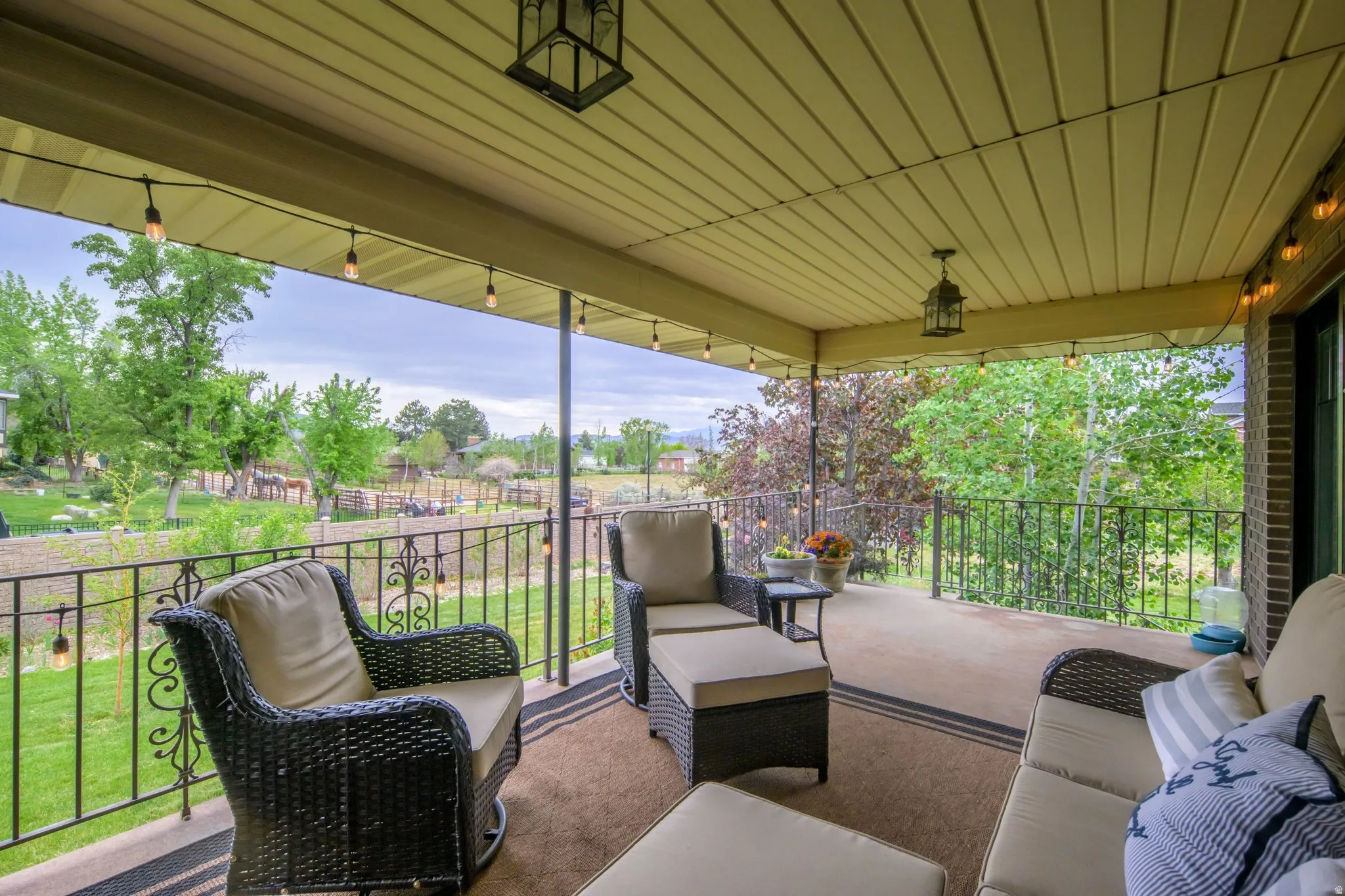 Covered outdoor patio featuring a concrete floor, black wrought iron railing, and a beadboard ceiling with recessed light fixtures