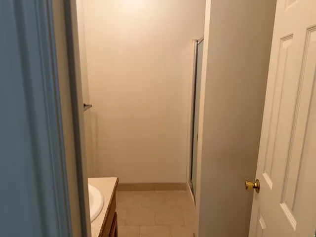 Bathroom featuring a vanity with a drop-in sink, solid surface countertop, wood-finish cabinetry, and tiled flooring
