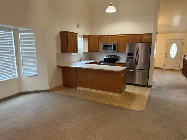 Kitchen featuring wood-finish cabinetry, stainless steel appliances, and a tiled backsplash