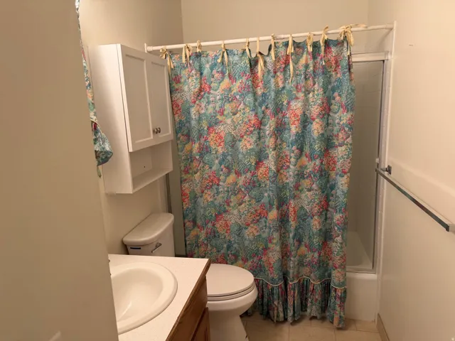 Built-in white storage cabinet, toilet, and a shower with a sliding glass door