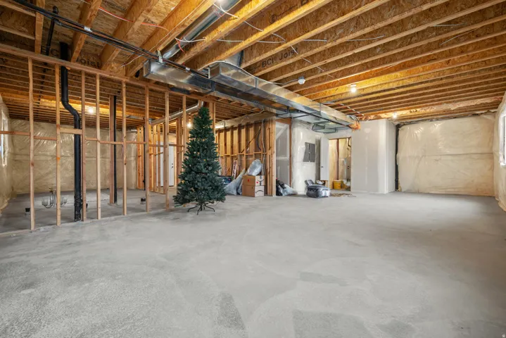 Unfinished lower level featuring exposed wood joists, structural framing, and a concrete floor