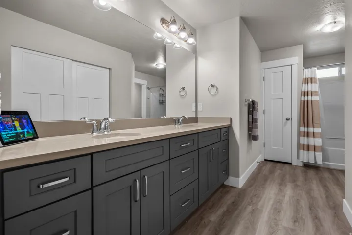 Double vanity with gray shaker cabinetry and chrome hardware, featuring a light-toned countertop and dual undermount sinks