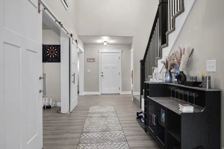 Entryway featuring wood-finish flooring and a staircase with dark wood banister and white risers