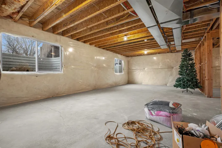 Unfinished lower level featuring exposed wood joists, concrete flooring, and multiple windows