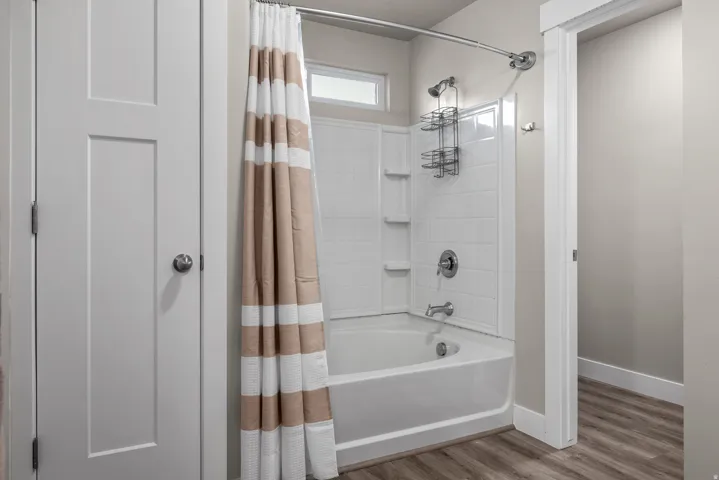 Tub and shower combination featuring a white tiled surround with integrated shelving and a chrome shower fixture