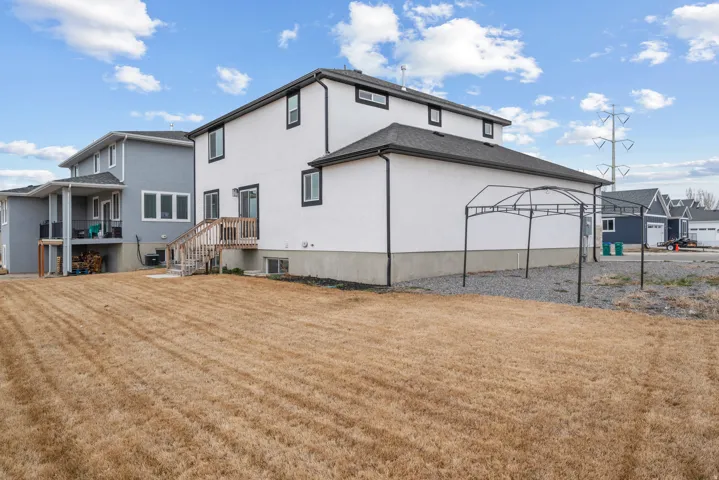 Modern stucco exterior featuring contrasting trim, a rear deck with wooden stairs, and a spacious backyard area