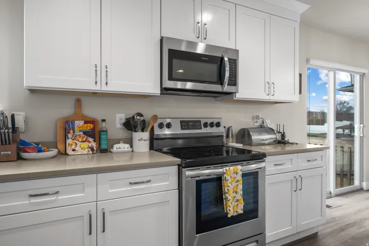 Kitchen featuring white shaker-style cabinetry, stainless steel appliances, and light-toned countertops