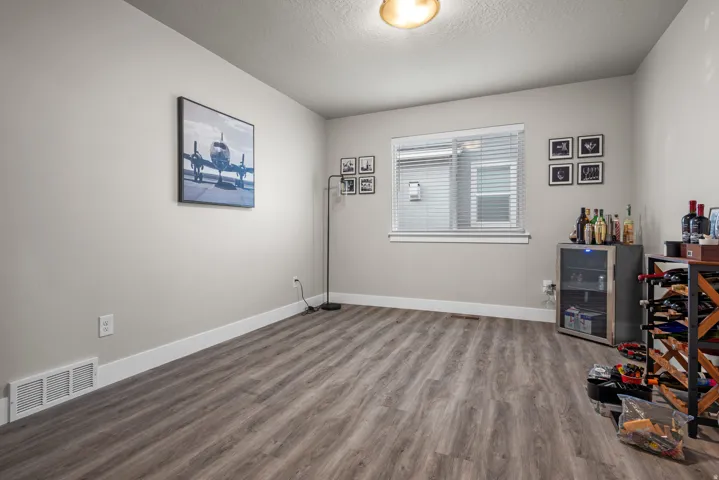 Spacious room featuring wood-finish flooring, light neutral wall tones, and a single window with blinds