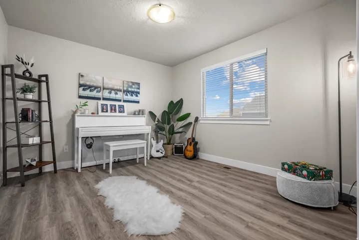 Spacious room featuring wood-finish flooring, a large window with blinds, and light neutral wall paint